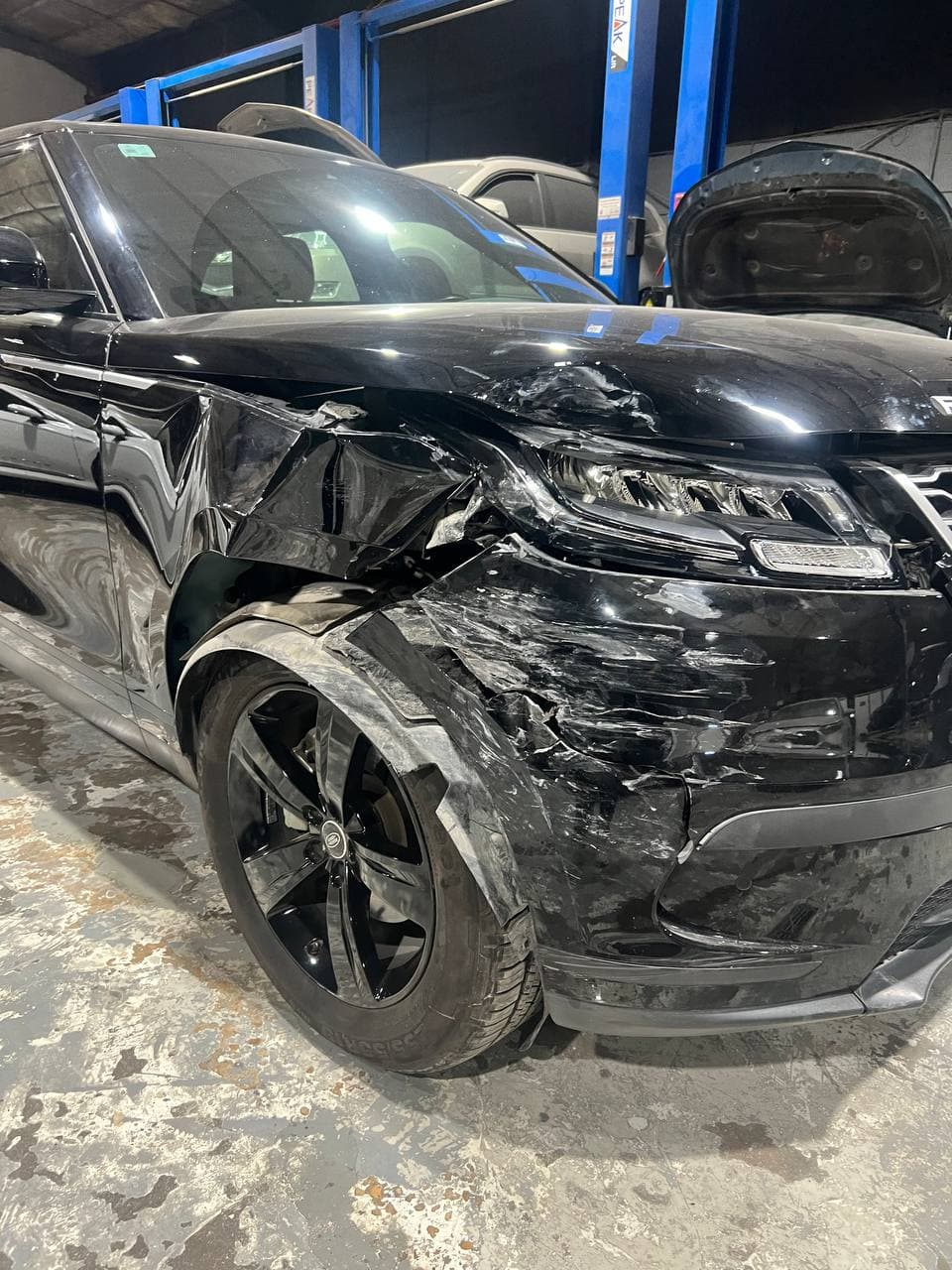 A white car with side damage waiting for repair.